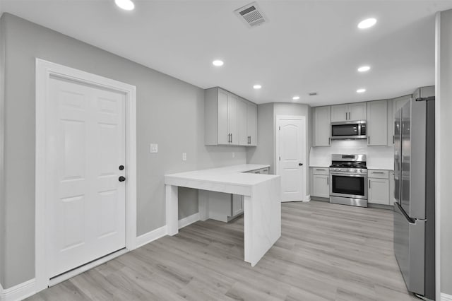 kitchen featuring recessed lighting, a peninsula, visible vents, light wood-style floors, and appliances with stainless steel finishes