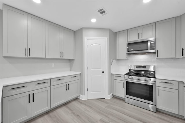 kitchen with light countertops, visible vents, backsplash, appliances with stainless steel finishes, and light wood-type flooring