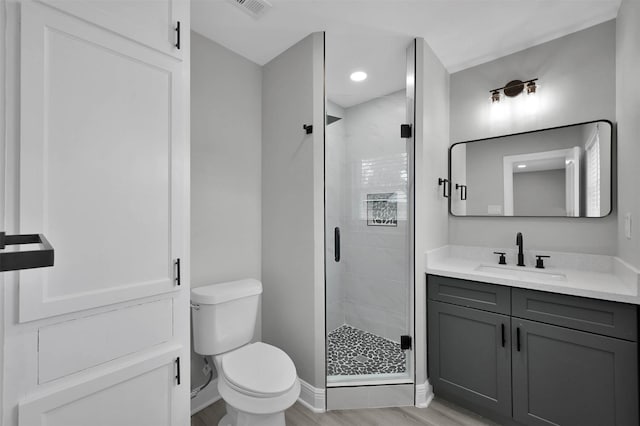 bathroom with toilet, a stall shower, wood finished floors, and vanity