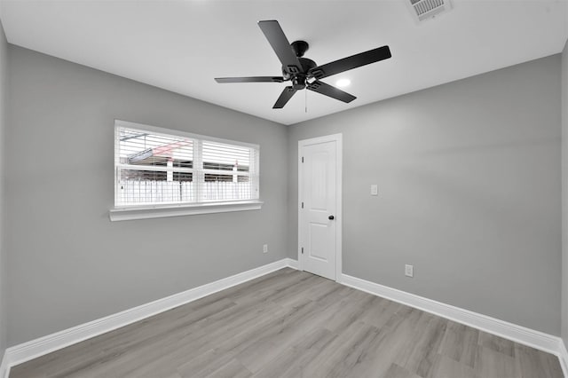 unfurnished room featuring a ceiling fan, wood finished floors, visible vents, and baseboards