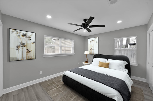 bedroom with multiple windows, wood finished floors, and baseboards