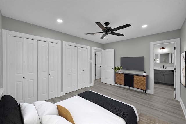 bedroom featuring multiple closets, recessed lighting, a sink, and light wood finished floors