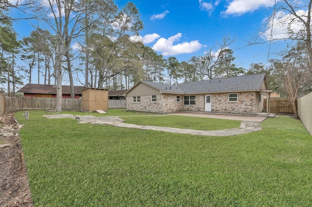 rear view of property featuring an outbuilding, a shed, a lawn, and a fenced backyard