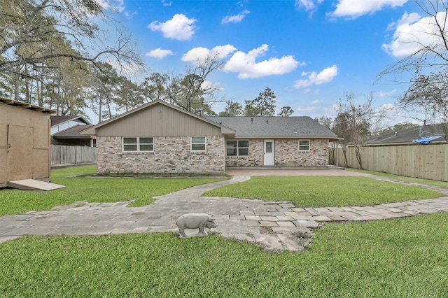 rear view of property featuring an outbuilding, brick siding, a yard, a patio, and a fenced backyard