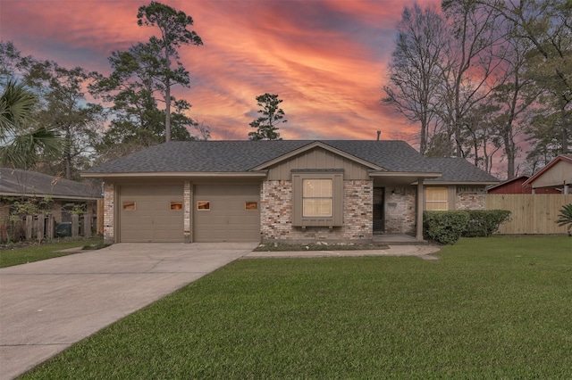 view of front facade featuring brick siding, a lawn, fence, a garage, and driveway