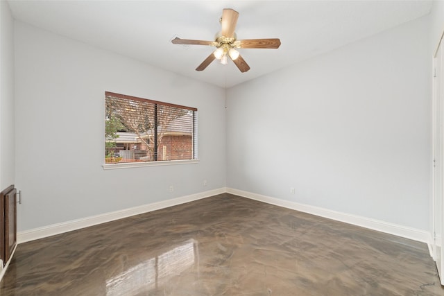 spare room with finished concrete flooring, a ceiling fan, and baseboards