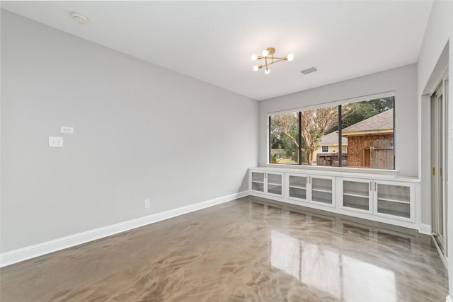 empty room with a chandelier, concrete floors, visible vents, and baseboards