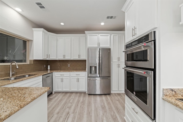 kitchen with backsplash, visible vents, stainless steel appliances, and a sink