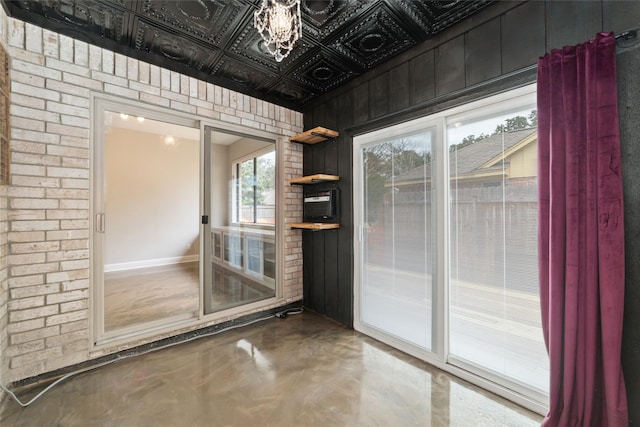 doorway with finished concrete flooring, brick wall, and an ornate ceiling