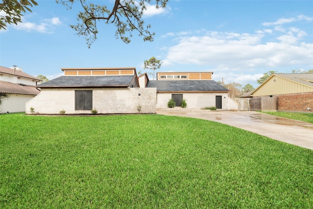 view of front facade featuring brick siding, a shingled roof, fence, concrete driveway, and a front yard