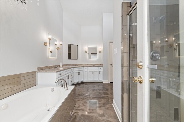 full bathroom featuring marble finish floor, double vanity, a shower stall, a jetted tub, and baseboards