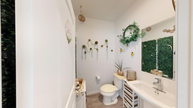 half bathroom featuring toilet, baseboards, and a sink