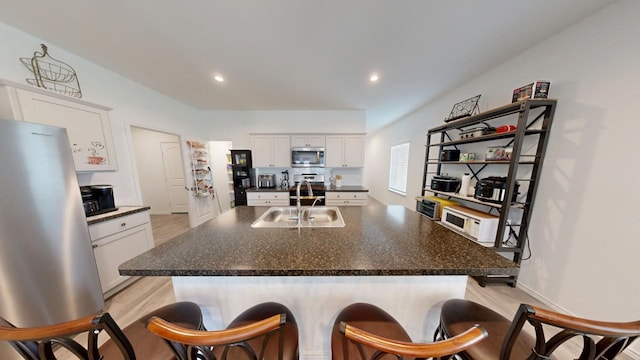 kitchen with dark countertops, white cabinetry, stainless steel appliances, and a sink