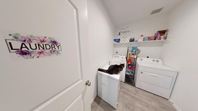 laundry room featuring light wood-type flooring, laundry area, visible vents, and independent washer and dryer