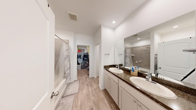 full bath with visible vents, a sink, a tile shower, and double vanity