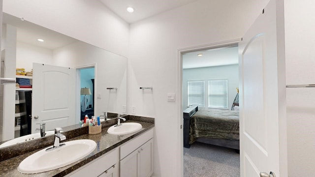 ensuite bathroom featuring double vanity, recessed lighting, a sink, and connected bathroom