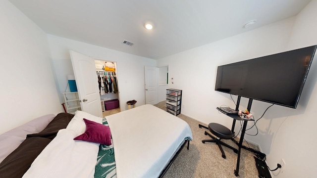 bedroom with a walk in closet, recessed lighting, visible vents, carpet flooring, and baseboards