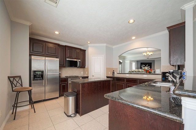 kitchen featuring dark brown cabinetry, light tile patterned floors, visible vents, stainless steel appliances, and a sink