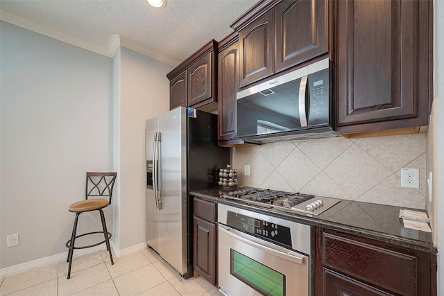 kitchen with light tile patterned floors, baseboards, decorative backsplash, stainless steel appliances, and dark brown cabinets