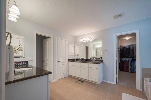 bathroom with visible vents, baseboards, tile patterned flooring, a spacious closet, and vanity