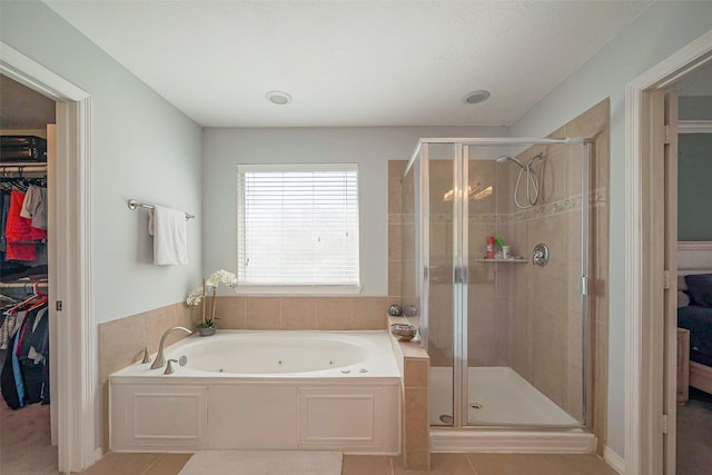 bathroom with a spacious closet, a tub with jets, tile patterned flooring, and a shower stall