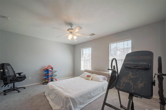 carpeted bedroom with visible vents, baseboards, ceiling fan, and a textured ceiling