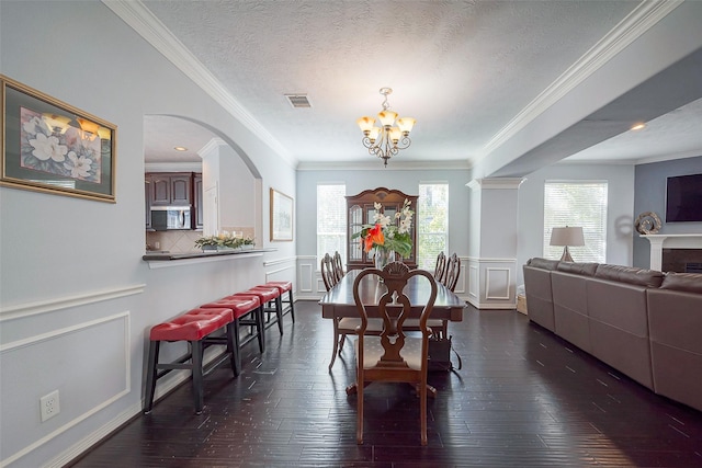 dining space with visible vents, a decorative wall, dark wood-type flooring, and a chandelier