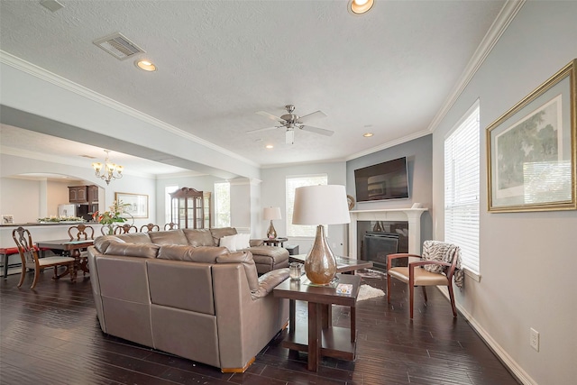 living room featuring visible vents, a premium fireplace, dark wood-type flooring, a textured ceiling, and crown molding