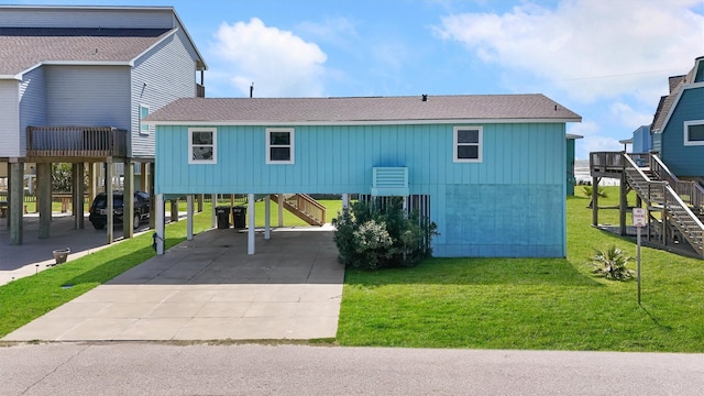 view of front facade with roof with shingles, stairs, a carport, and a front yard