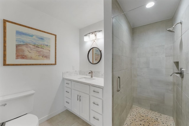 bathroom featuring baseboards, toilet, tile patterned flooring, vanity, and a shower stall