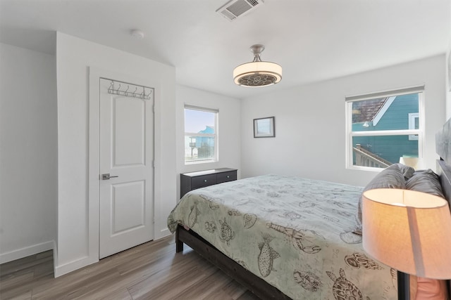 bedroom featuring wood finished floors, visible vents, and baseboards