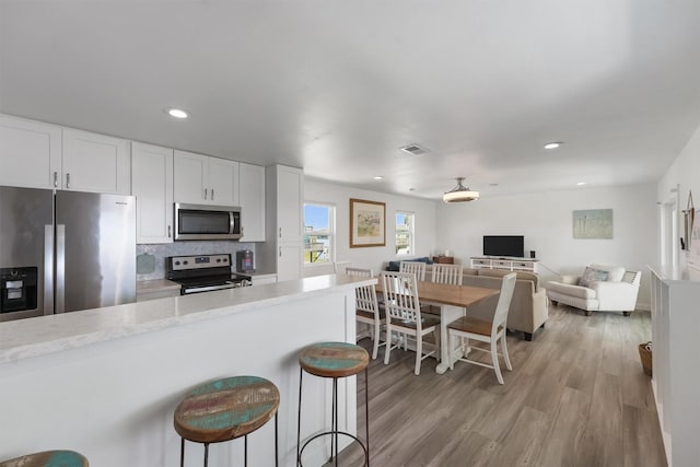 kitchen featuring visible vents, white cabinetry, a kitchen breakfast bar, light countertops, and appliances with stainless steel finishes