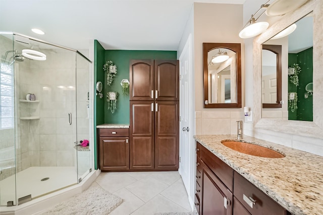 bathroom with tile patterned floors, tasteful backsplash, vanity, and a shower stall