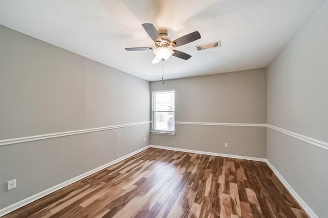 empty room with visible vents, baseboards, wood finished floors, and a ceiling fan