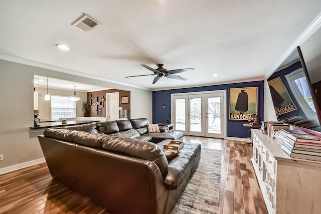 living area with visible vents, a healthy amount of sunlight, french doors, and wood finished floors