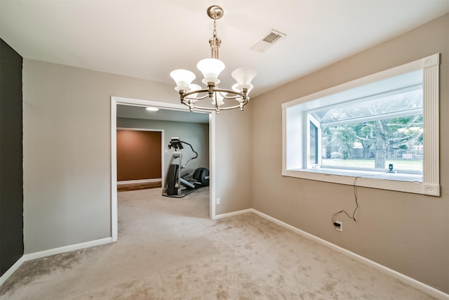 empty room featuring visible vents, light carpet, a notable chandelier, and baseboards