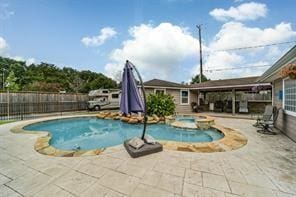 view of swimming pool with a patio, fence, and a pool with connected hot tub