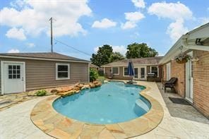 outdoor pool featuring a patio area, french doors, and an outbuilding