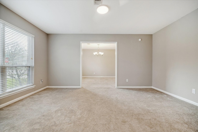 spare room featuring an inviting chandelier, carpet, baseboards, and a wealth of natural light