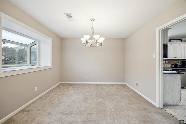 spare room with a chandelier, visible vents, light colored carpet, and baseboards