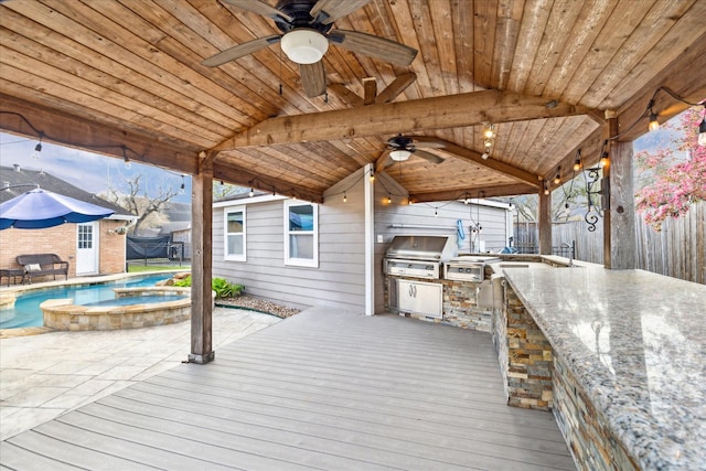 deck with grilling area, a fenced backyard, a ceiling fan, and exterior kitchen