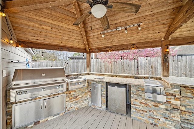 deck with area for grilling, exterior kitchen, a ceiling fan, and fence