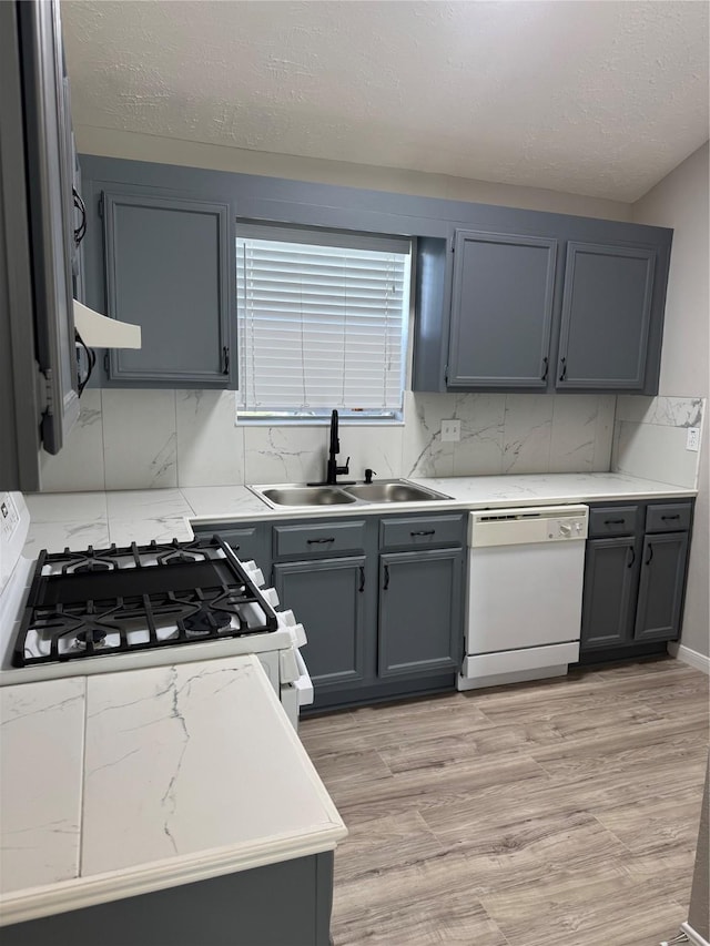 kitchen with tasteful backsplash, white appliances, a sink, and gray cabinetry