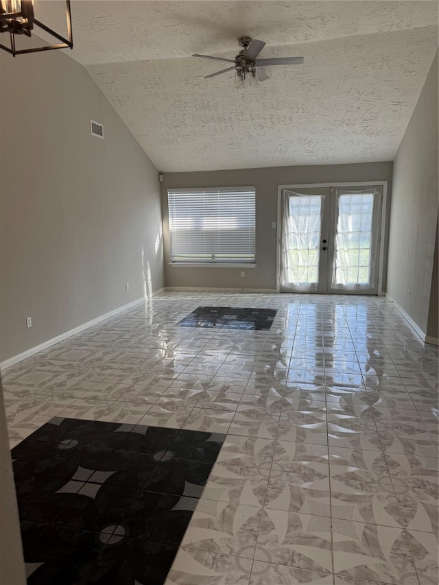 unfurnished living room with baseboards, visible vents, vaulted ceiling, a textured ceiling, and french doors