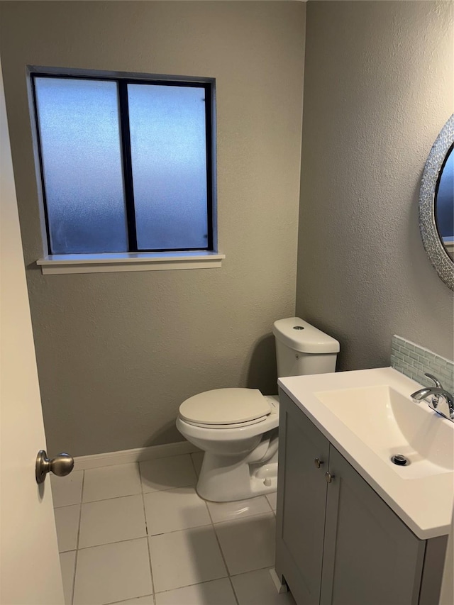 half bath featuring baseboards, a textured wall, toilet, tile patterned flooring, and vanity