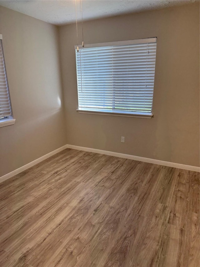 empty room with baseboards and wood finished floors