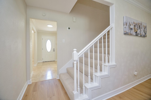 foyer with stairway, ornamental molding, baseboards, and wood finished floors