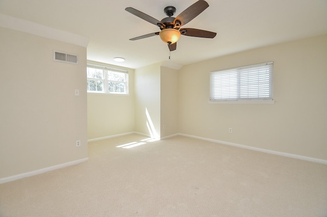 empty room featuring visible vents, light colored carpet, and baseboards