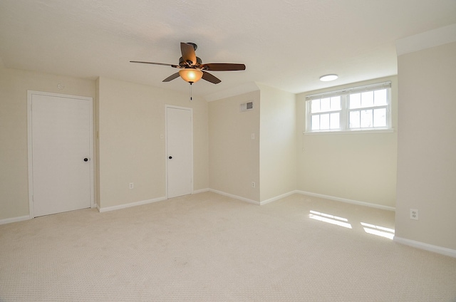 unfurnished room featuring visible vents, light colored carpet, and baseboards