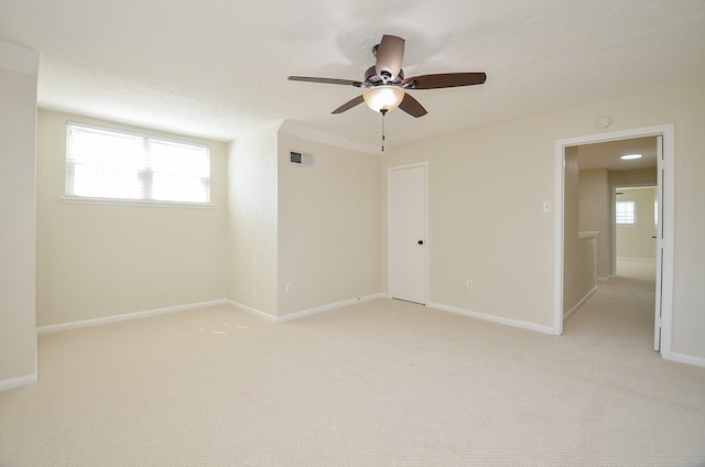 spare room featuring baseboards, visible vents, plenty of natural light, and light carpet